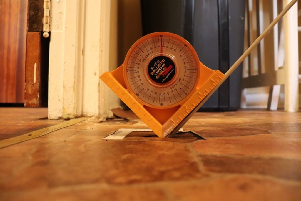 An angle finder measuring the path of a bullet into the kitchen floor